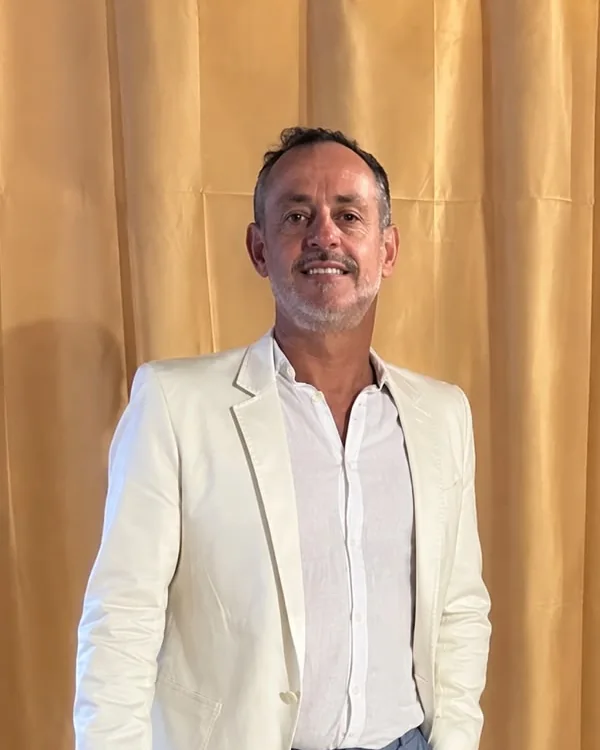 Júnior Arcoverde, sorrindo, de blazer branco